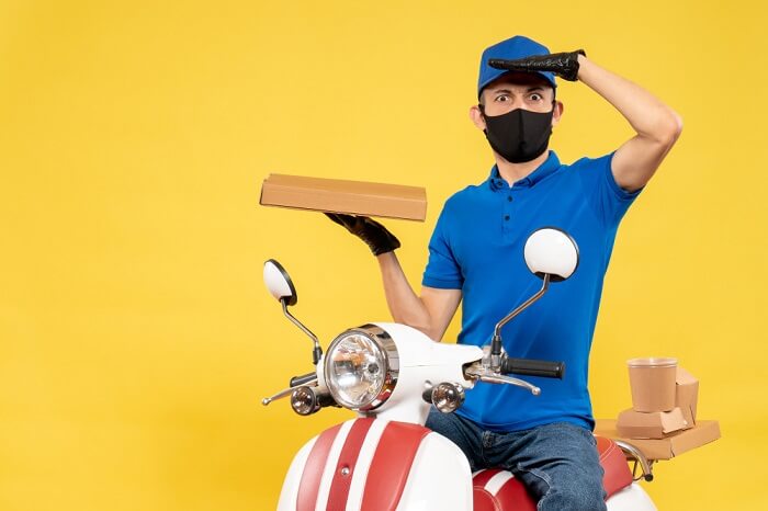 front view male courier blue uniform holding food box yellow pandemic bike covid delivery virus work service job